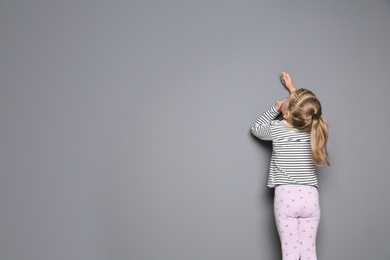 Photo of Little child drawing with colorful chalk on gray background. Space for design