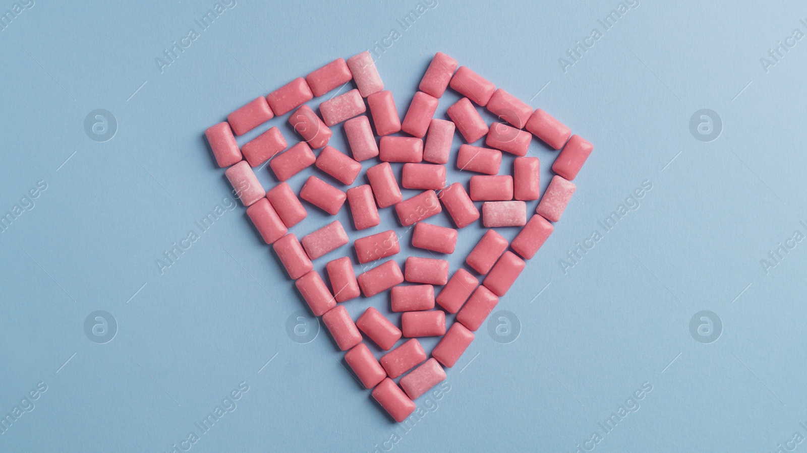 Photo of Heart made of sweet chewing gums on light blue background, top view