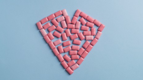 Heart made of sweet chewing gums on light blue background, top view