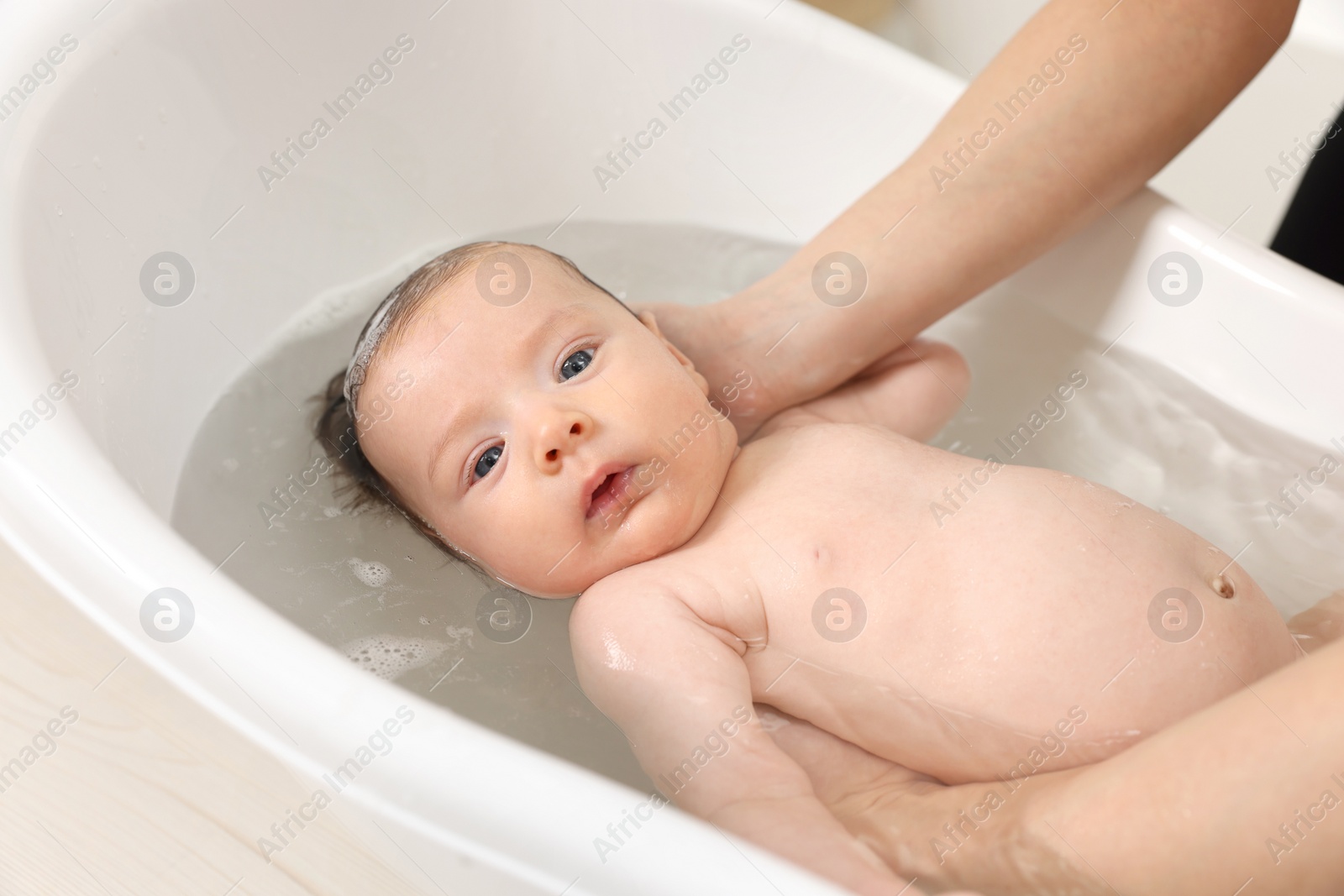 Photo of Mother bathing her little baby in bathtub, closeup