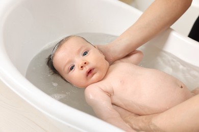 Mother bathing her little baby in bathtub, closeup