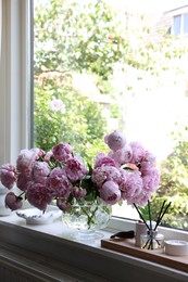 Beautiful pink peonies in vase on window sill, space for text. Interior design