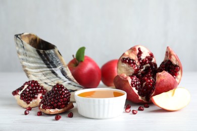 Honey, pomegranate, apples and shofar on white wooden table. Rosh Hashana holiday
