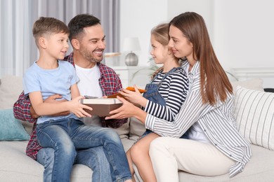 Photo of Happy family presenting each other with gifts on sofa at home