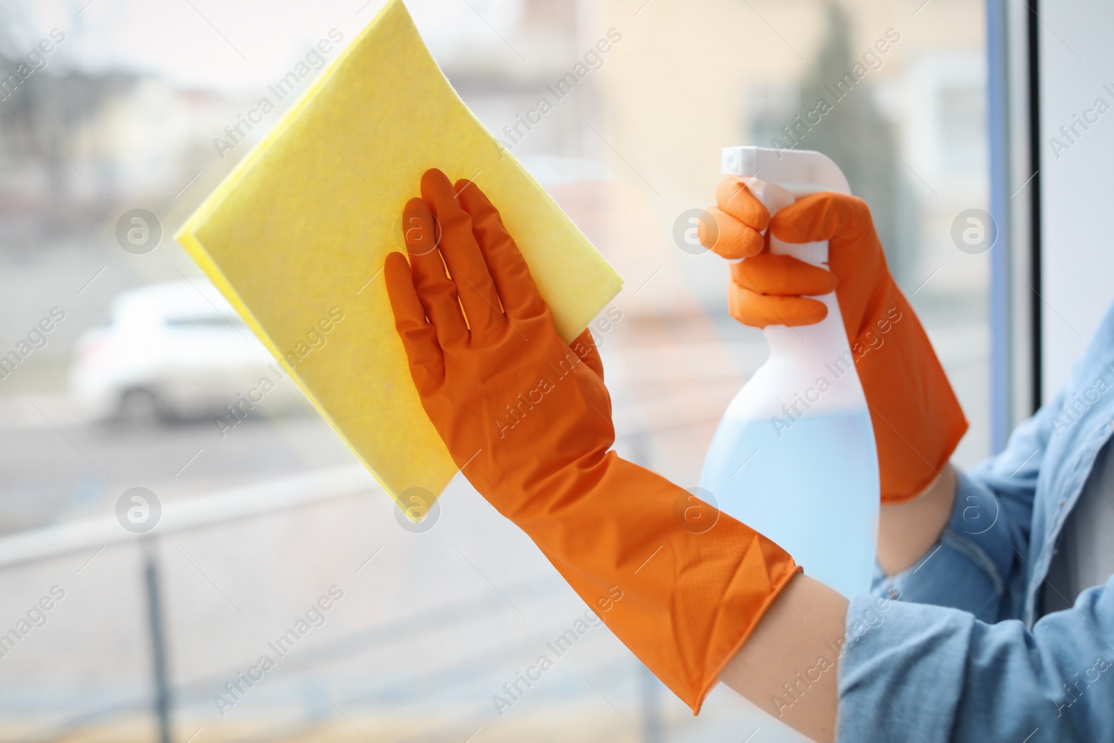 Photo of Young woman cleaning window glass at home, closeup