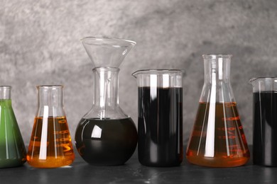 Beakers and flasks with different types of oil on grey textured table