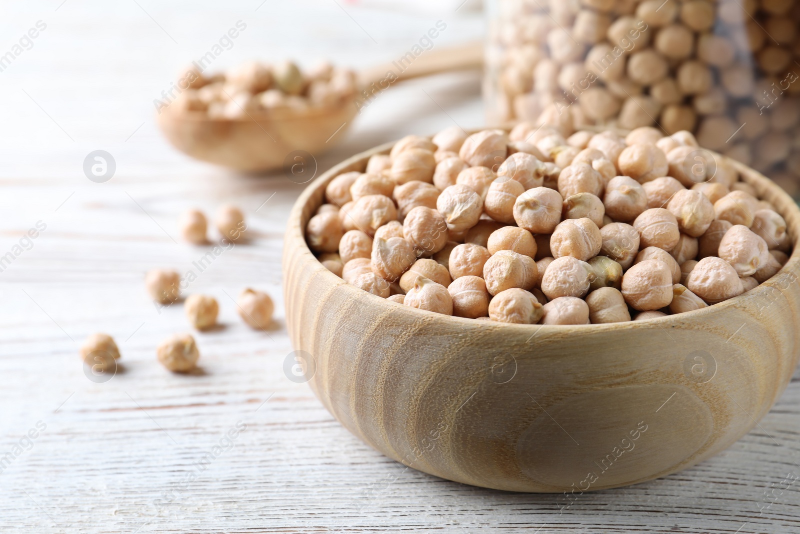 Photo of Raw chickpeas on white wooden table, closeup