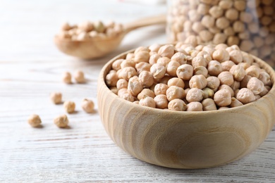 Photo of Raw chickpeas on white wooden table, closeup