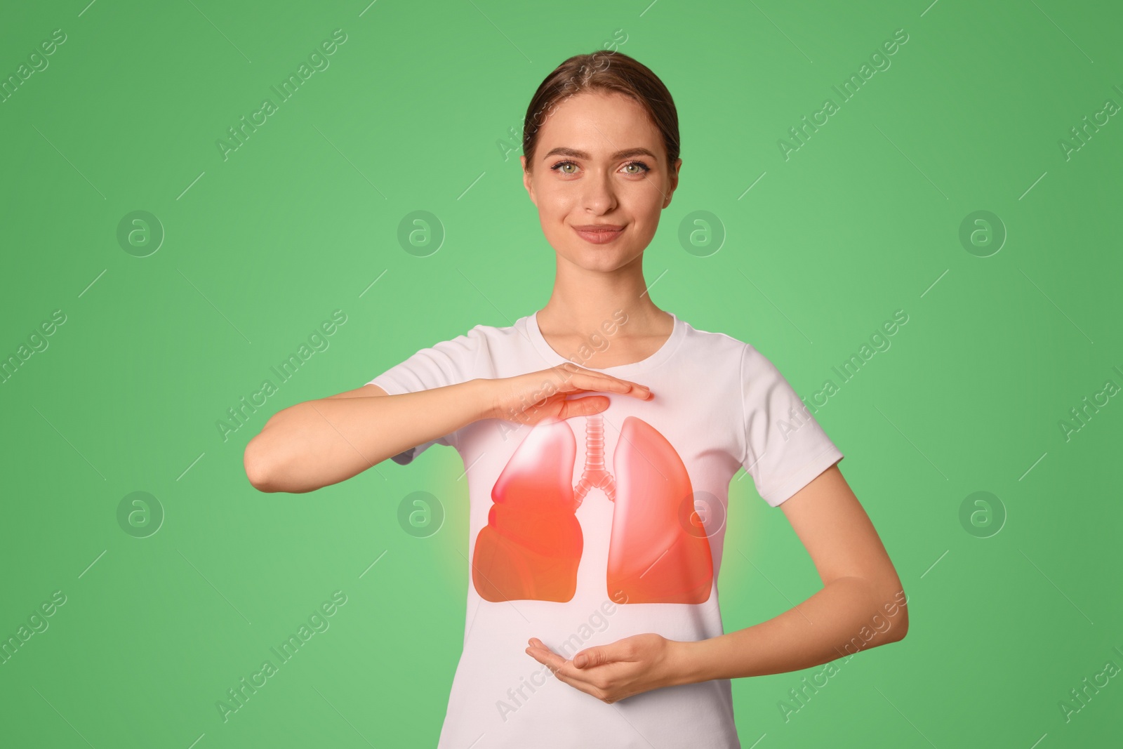 Image of Young woman holding hands near chest with illustration of lungs on green background, closeup