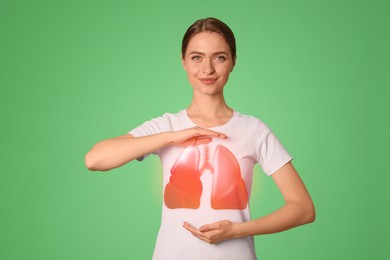 Young woman holding hands near chest with illustration of lungs on green background, closeup