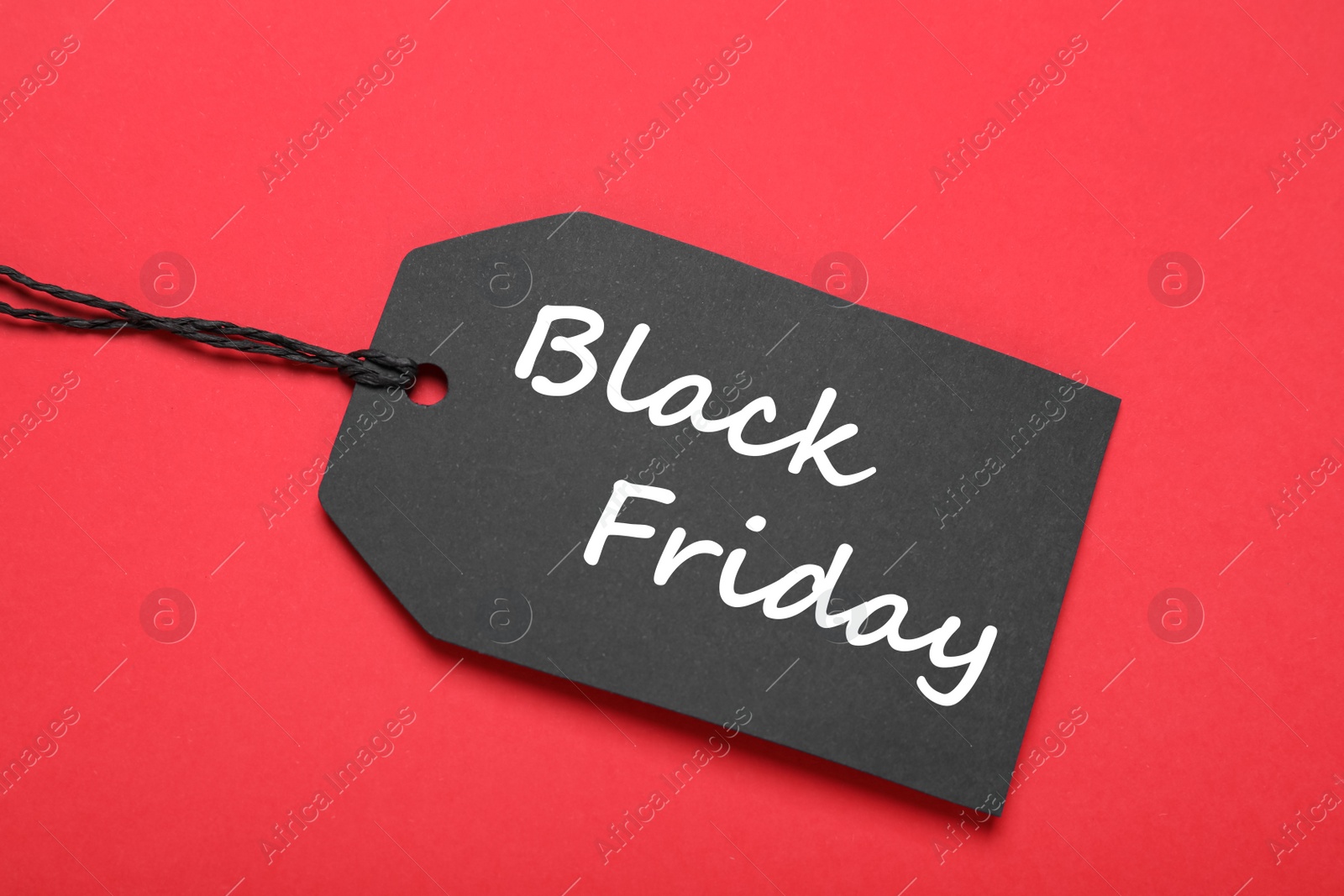 Photo of Black Friday tag on red background, top view