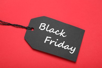 Photo of Black Friday tag on red background, top view