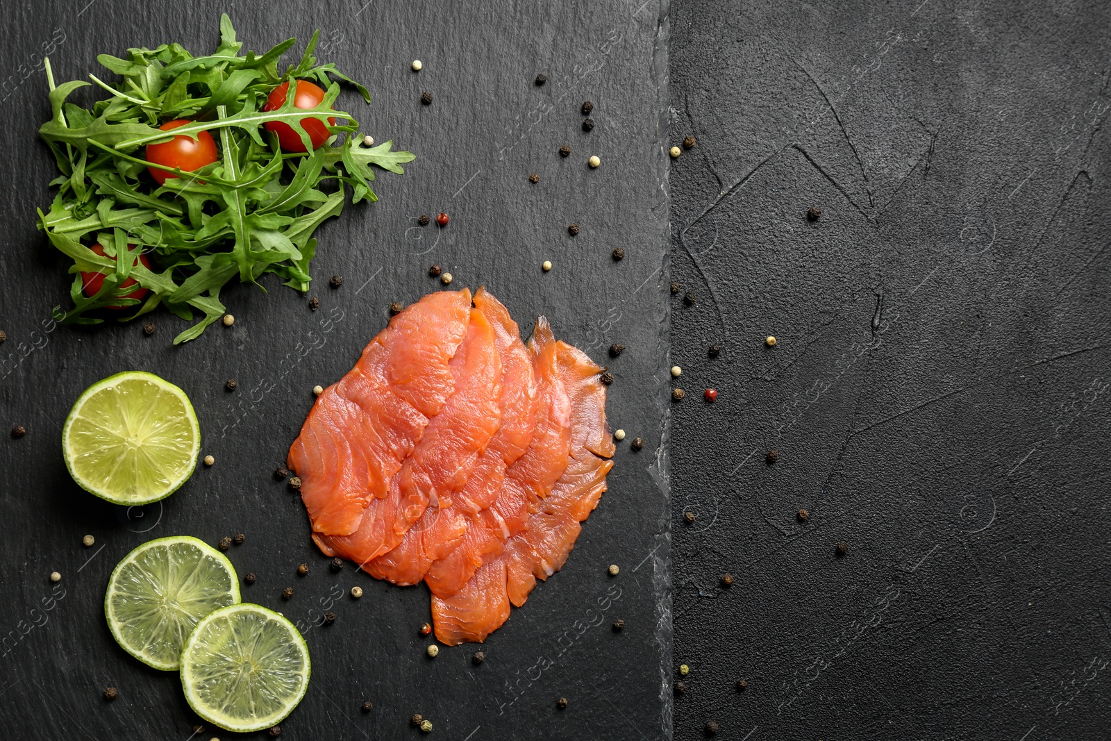 Photo of Fresh sliced salmon fillet with arugula and lemon on slate plate, top view