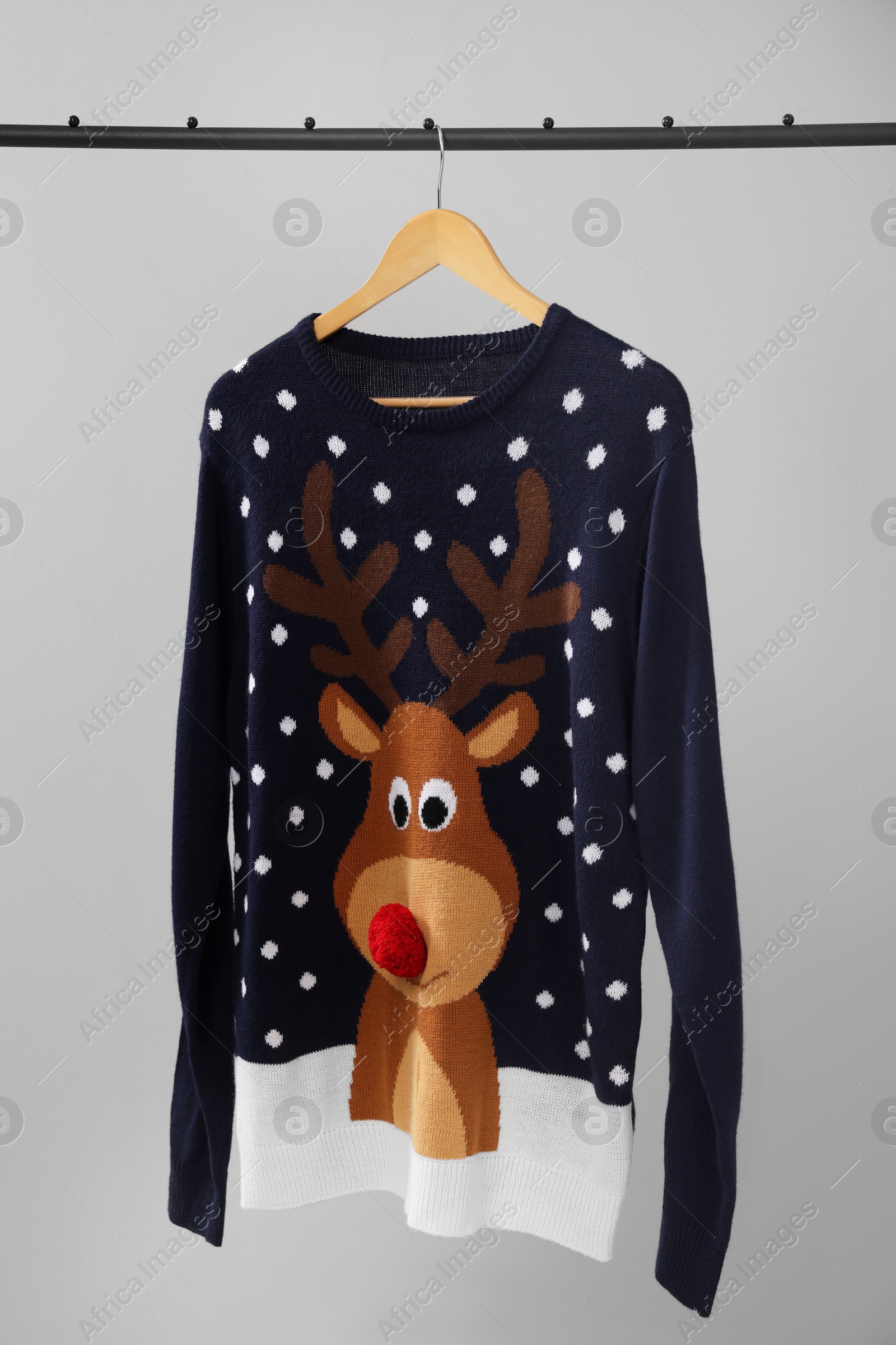 Photo of Rack with Christmas sweater on light background