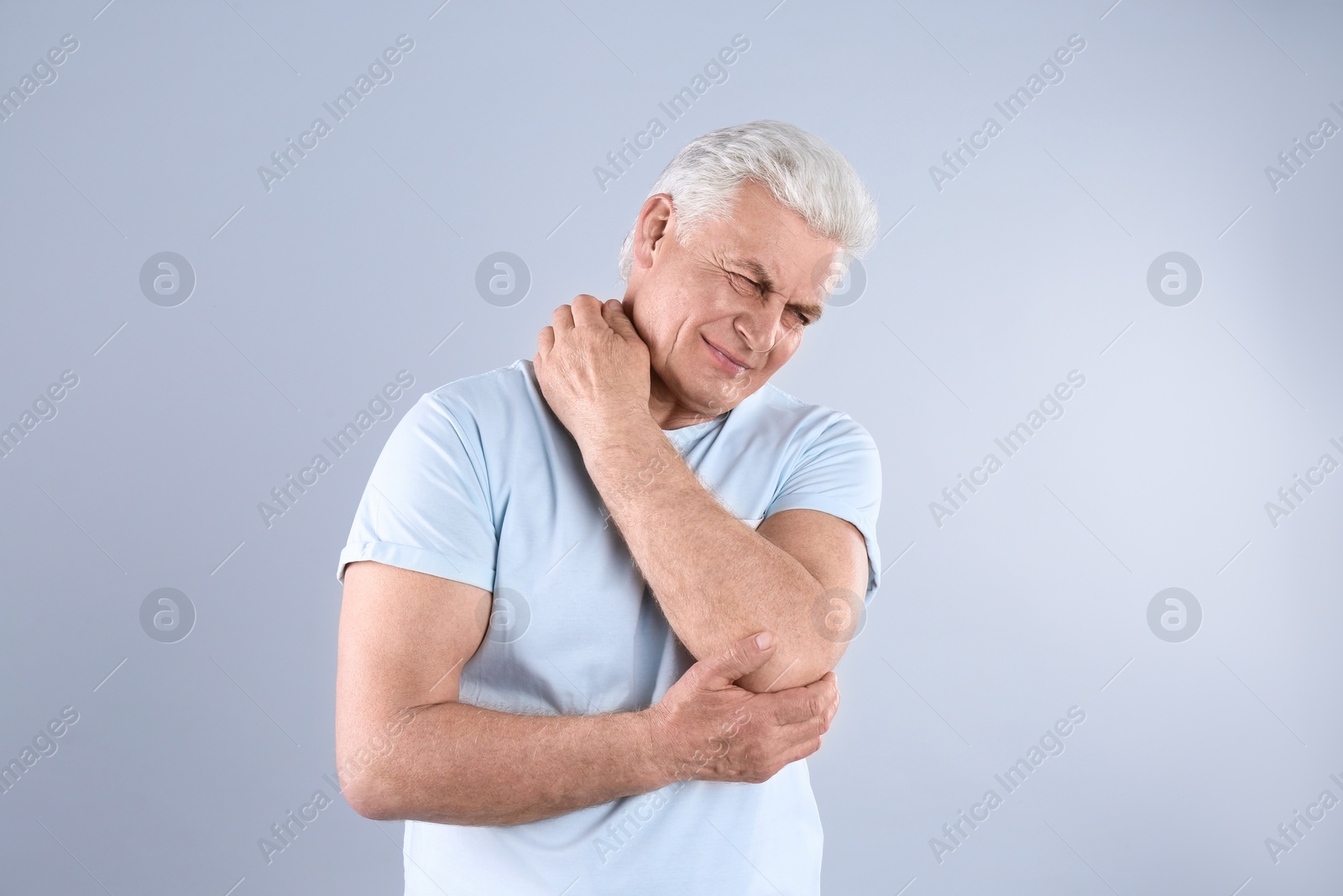 Photo of Senior man scratching neck on grey background. Allergy symptom