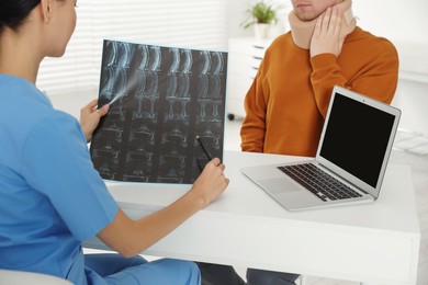 Photo of Doctor with neck MRI image consulting patient in clinic, closeup