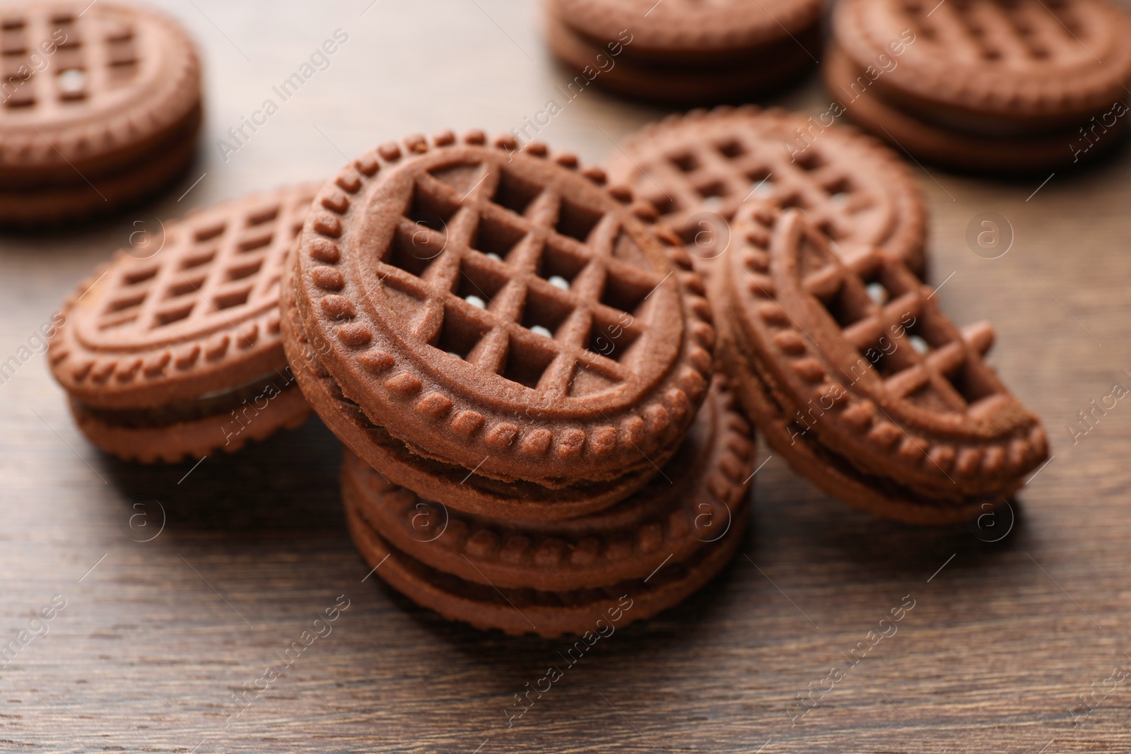 Photo of Tasty chocolate sandwich cookies with cream on wooden table, closeup