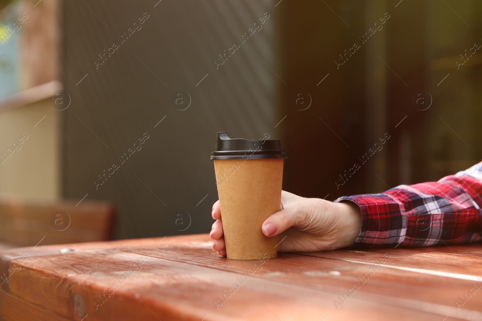 Photo of Man with takeaway coffee cup at wooden table outdoors, closeup. Space for text