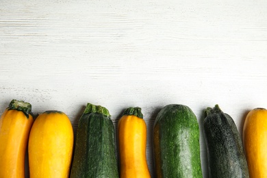 Photo of Fresh ripe zucchinis on white wooden table, flat lay. Space for text