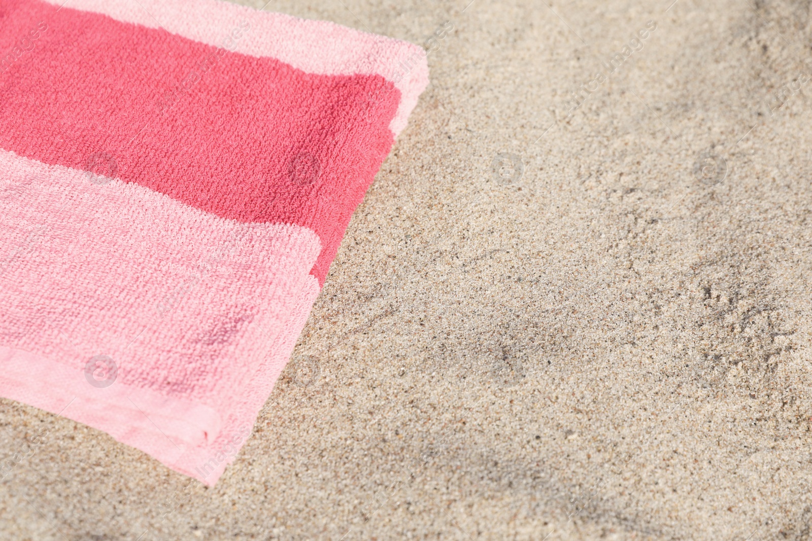 Photo of Soft pink beach towel on sand, space for text