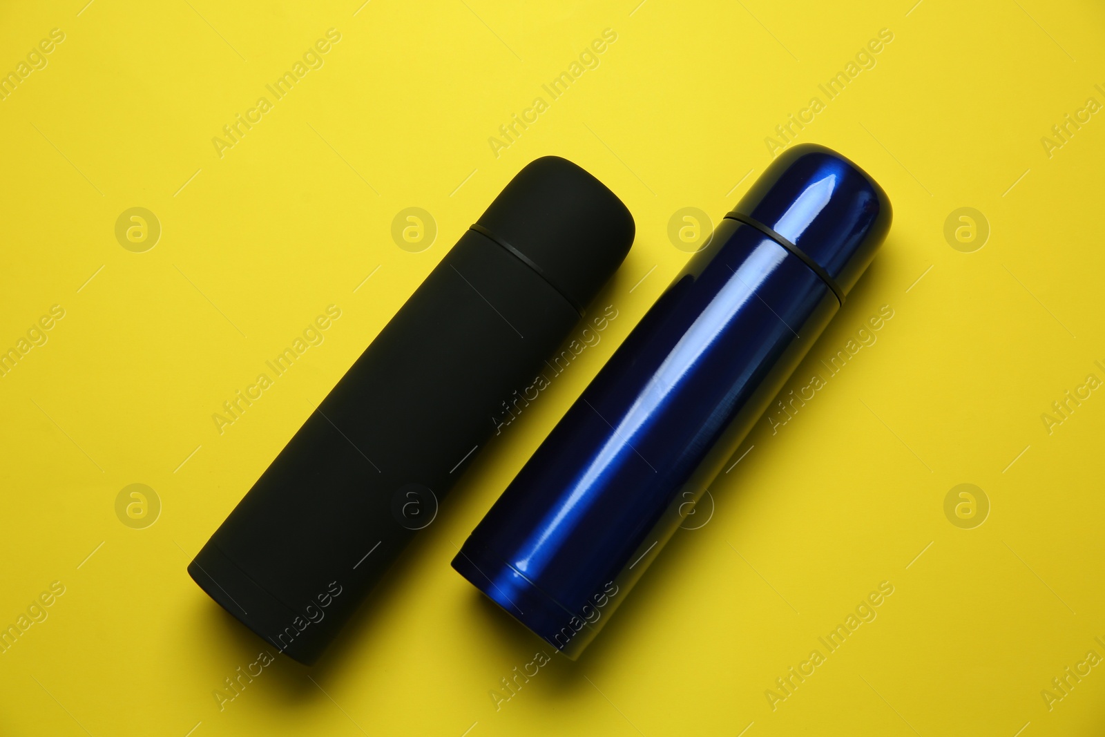 Photo of New modern thermoses on yellow background, flat lay