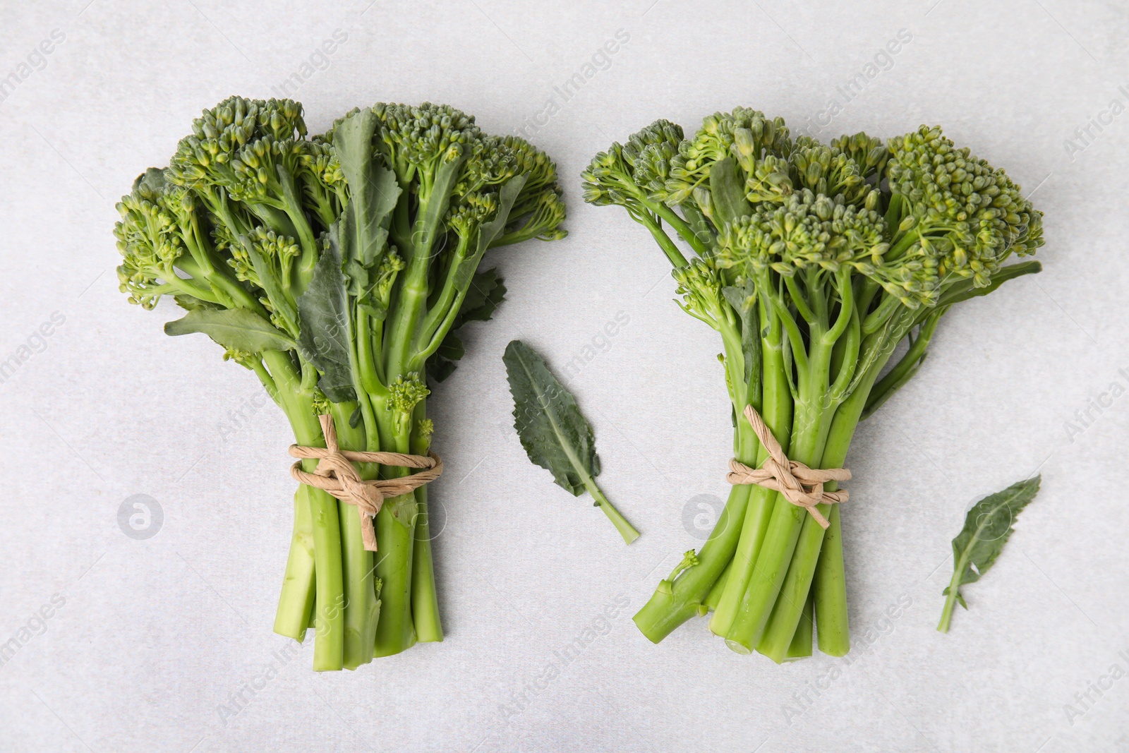 Photo of Fresh raw broccolini on white table, flat lay. Healthy food