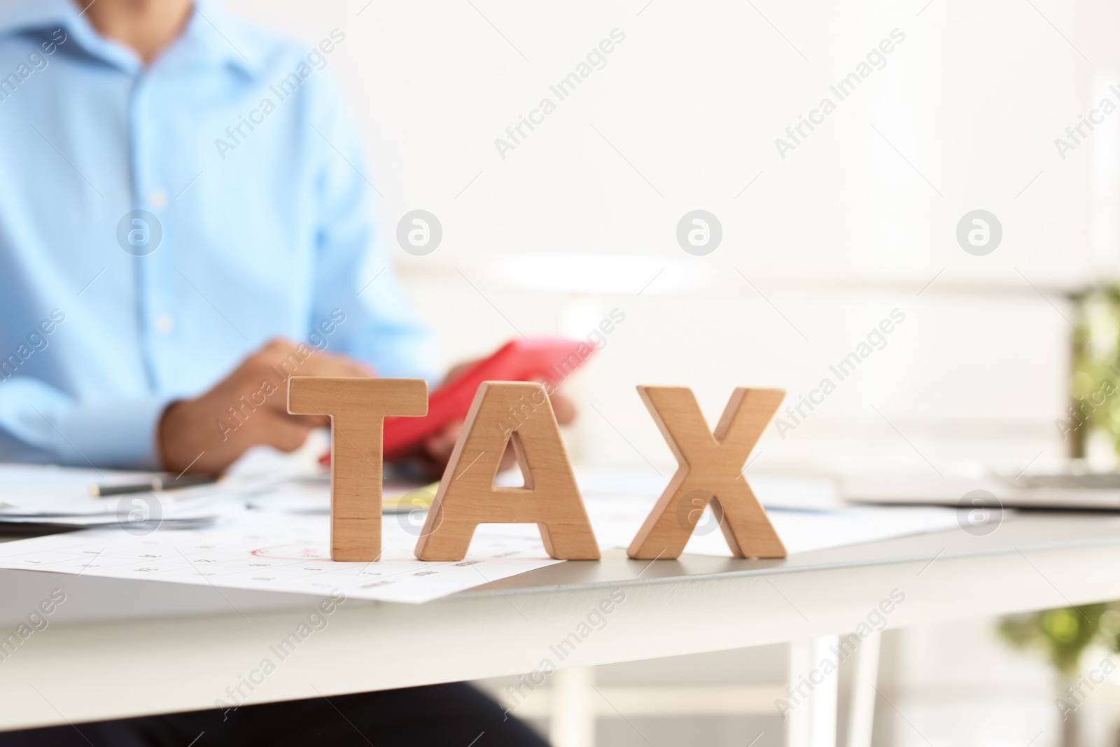 Photo of Word TAX and blurred accountant on background