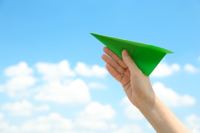 Woman holding paper plane against blue sky, closeup. Space for text