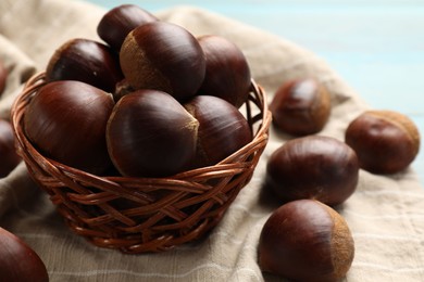 Photo of Wicker bowl with roasted edible sweet chestnuts on table, closeup