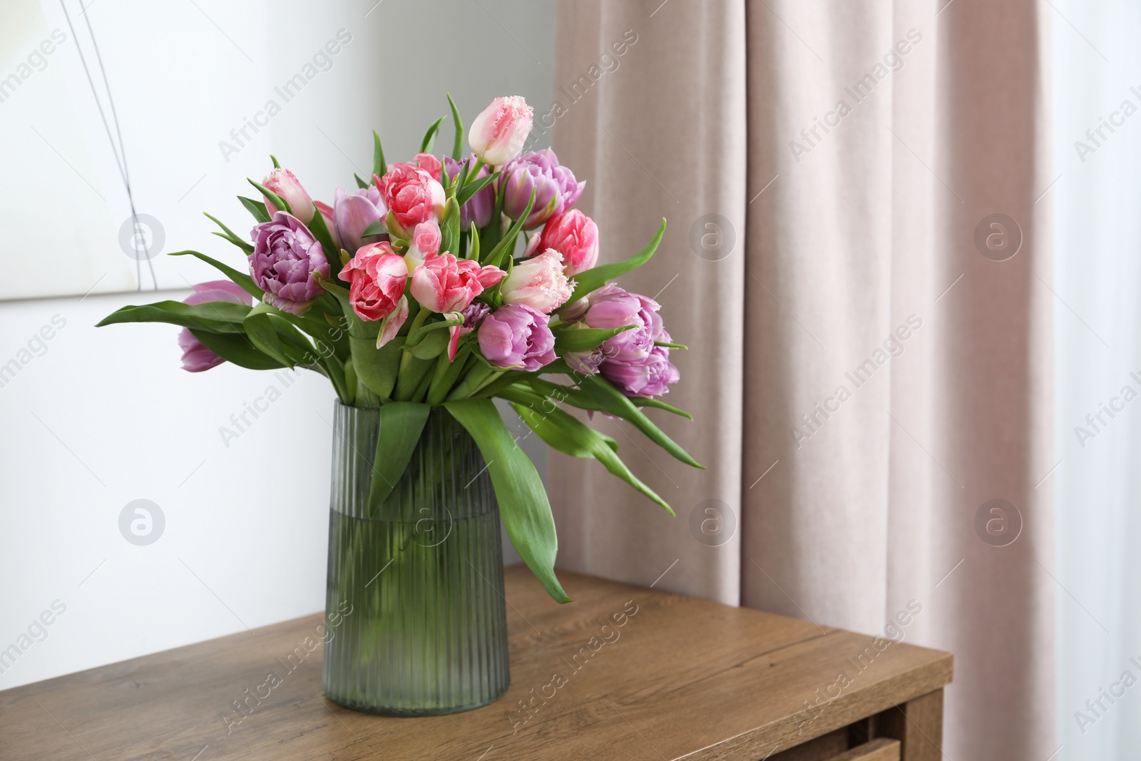 Photo of Beautiful bouquet of colorful tulip flowers on wooden table indoors. Space for text