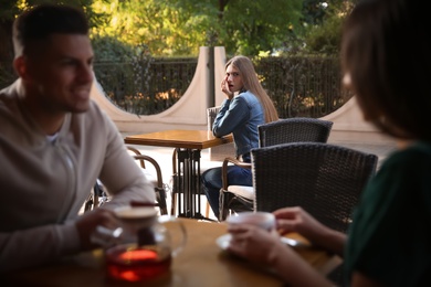 Photo of Jealous ex girlfriend spying on couple in outdoor cafe