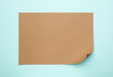 Photo of Sheet of brown paper on light blue background, top view