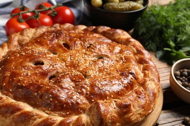 Photo of Tasty homemade pie and ingredients on wooden table, closeup