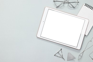 Photo of Flat lay composition with modern tablet on light grey background. Space for text