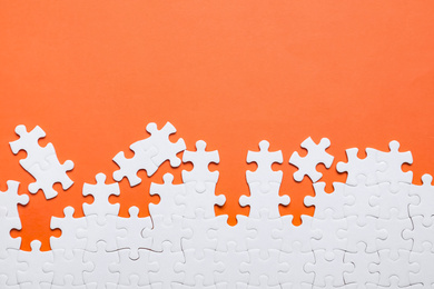 Photo of Blank white puzzle pieces on orange background, flat lay. Space for text