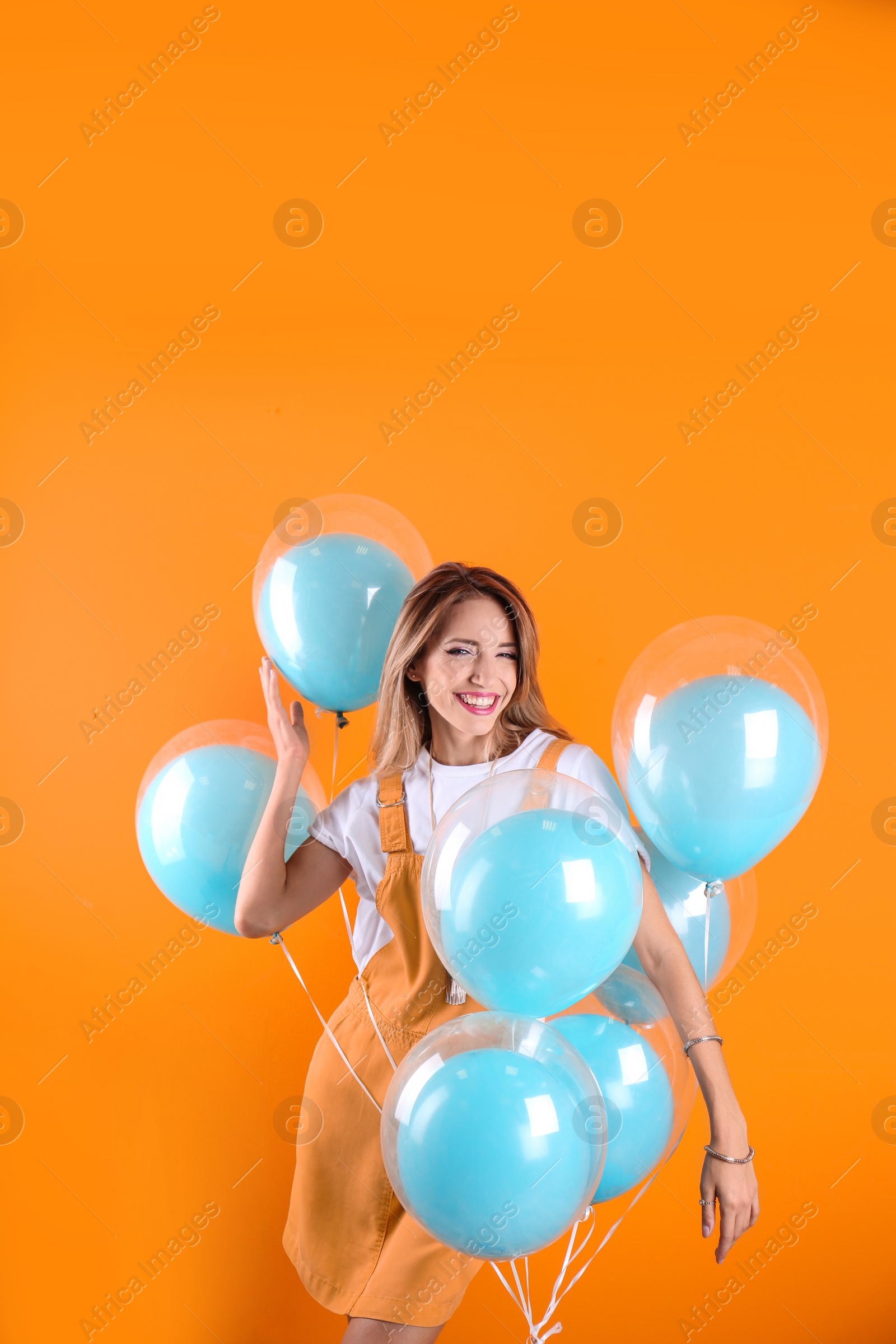 Photo of Young woman with air balloons on color background