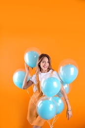 Young woman with air balloons on color background