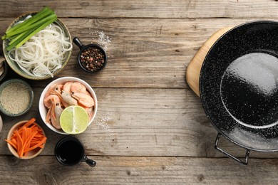 Photo of Flat lay composition with black wok, spices and products on wooden table