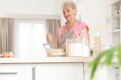 Portrait of beautiful grandmother cooking in kitchen