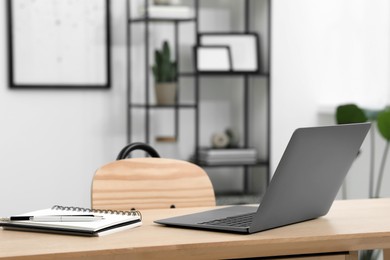 Home workspace. Laptop and stationery on wooden desk in room