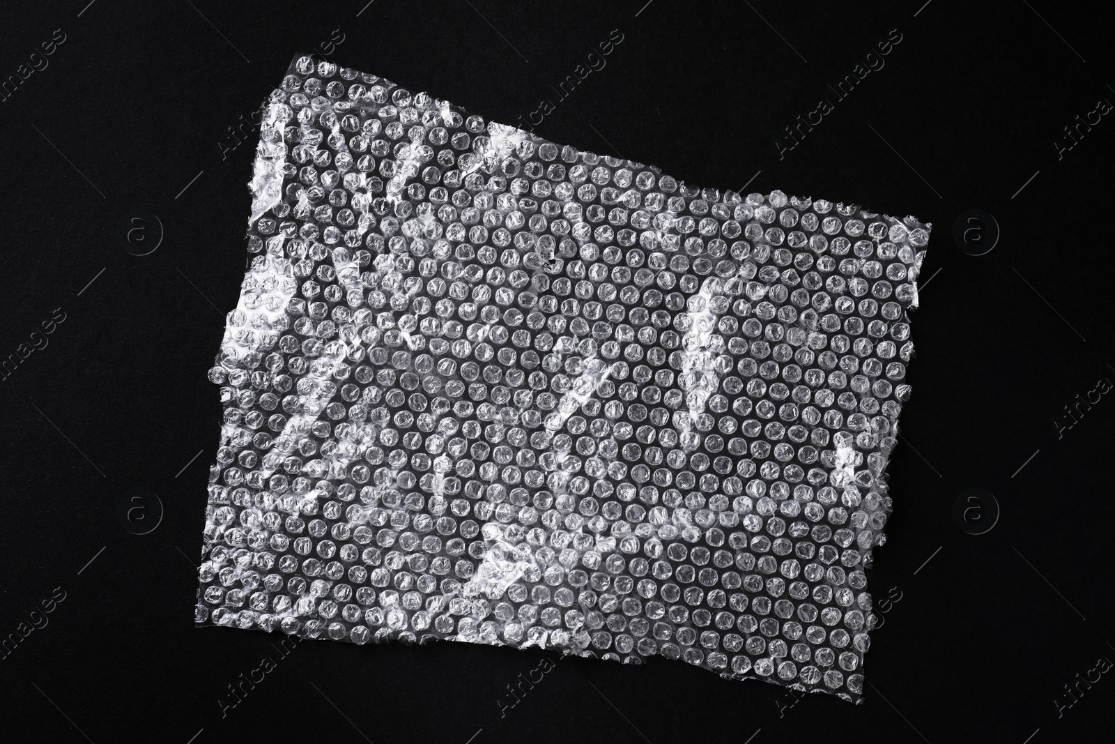 Photo of Transparent bubble wrap on black background, top view