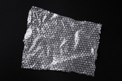 Photo of Transparent bubble wrap on black background, top view