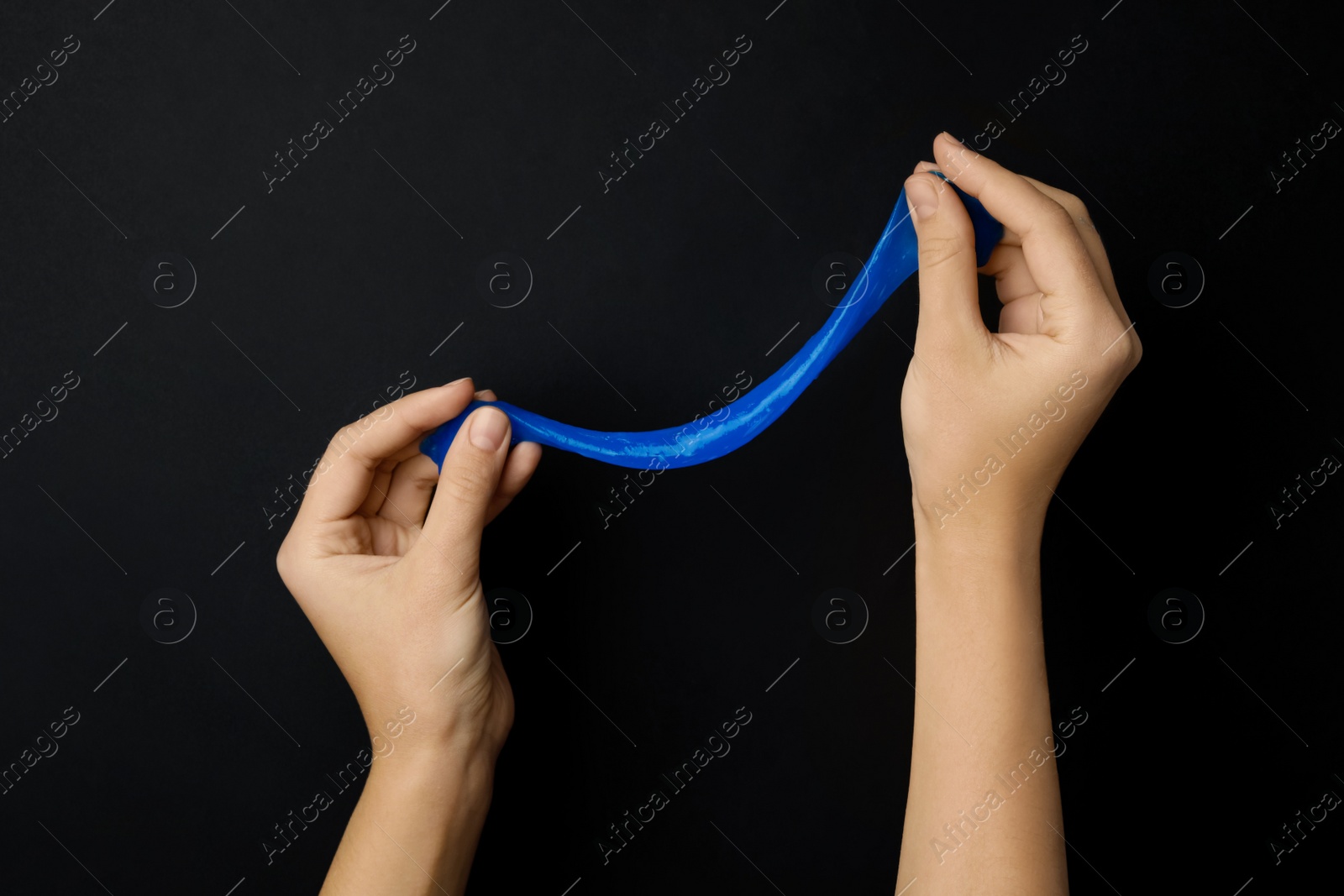 Photo of Woman playing with blue slime on black background, closeup. Antistress toy