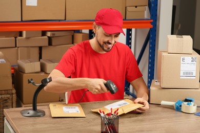 Post office worker with scanner reading parcel barcode at counter indoors