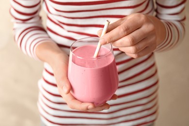 Woman with glass of tasty smoothie on beige background, closeup