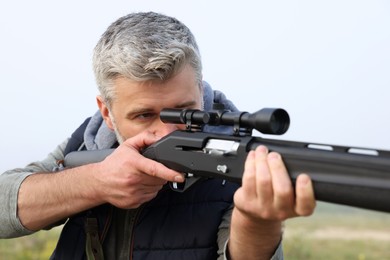 Photo of Man aiming with hunting rifle outdoors, closeup