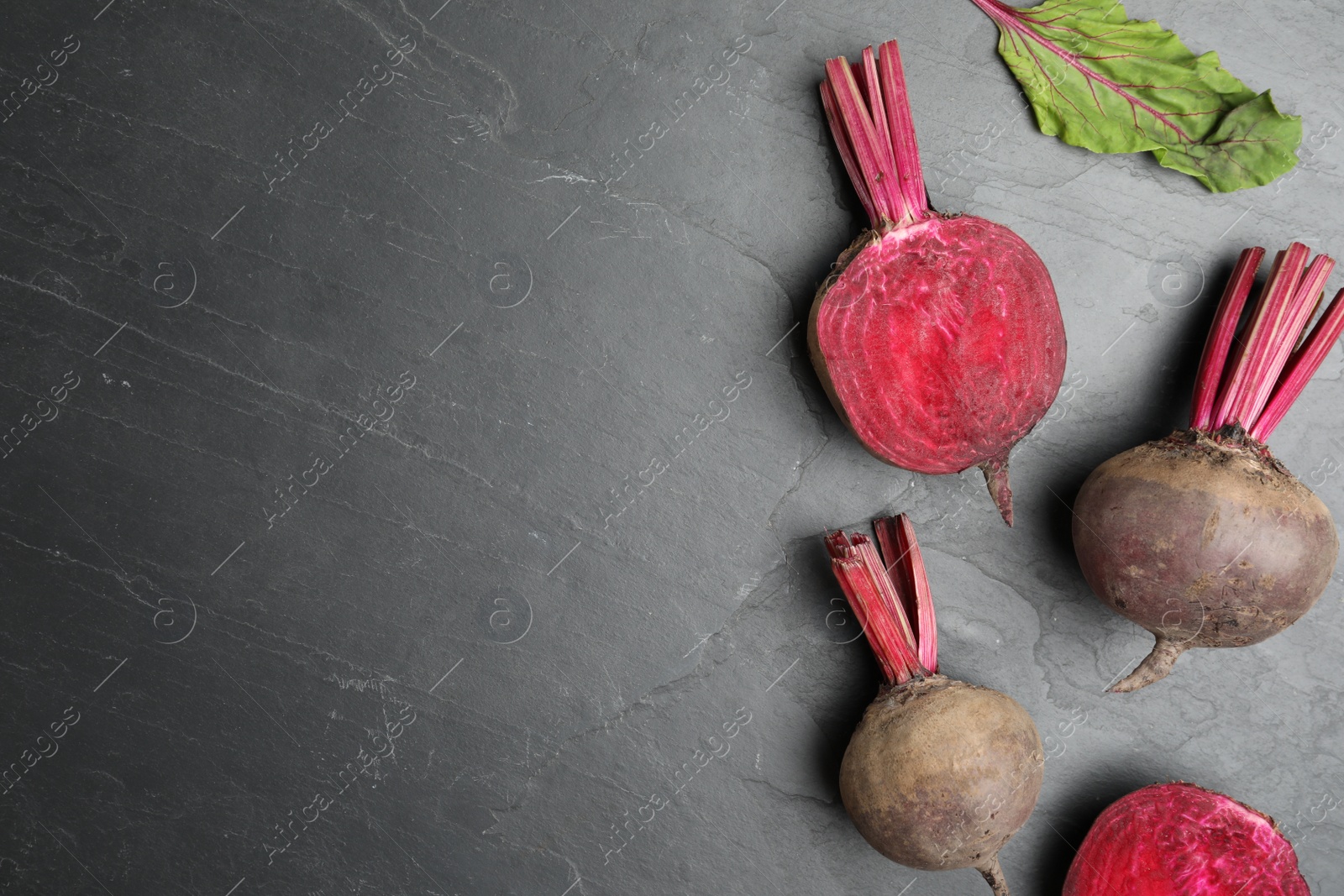 Photo of Cut and whole raw beets on grey table, flat lay. Space for text