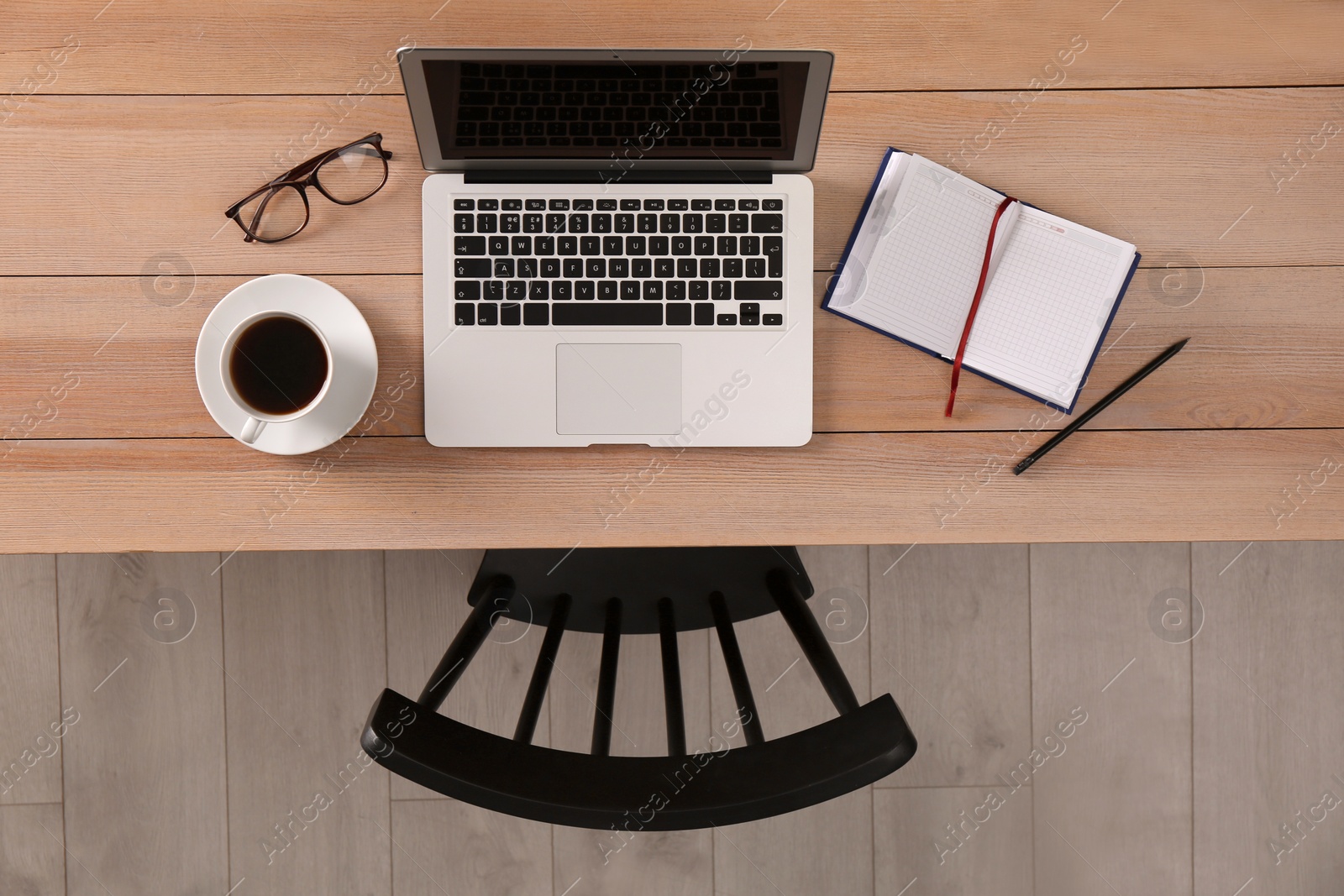 Photo of Chair near wooden table with laptop, cup of coffee and stationery indoors, top view