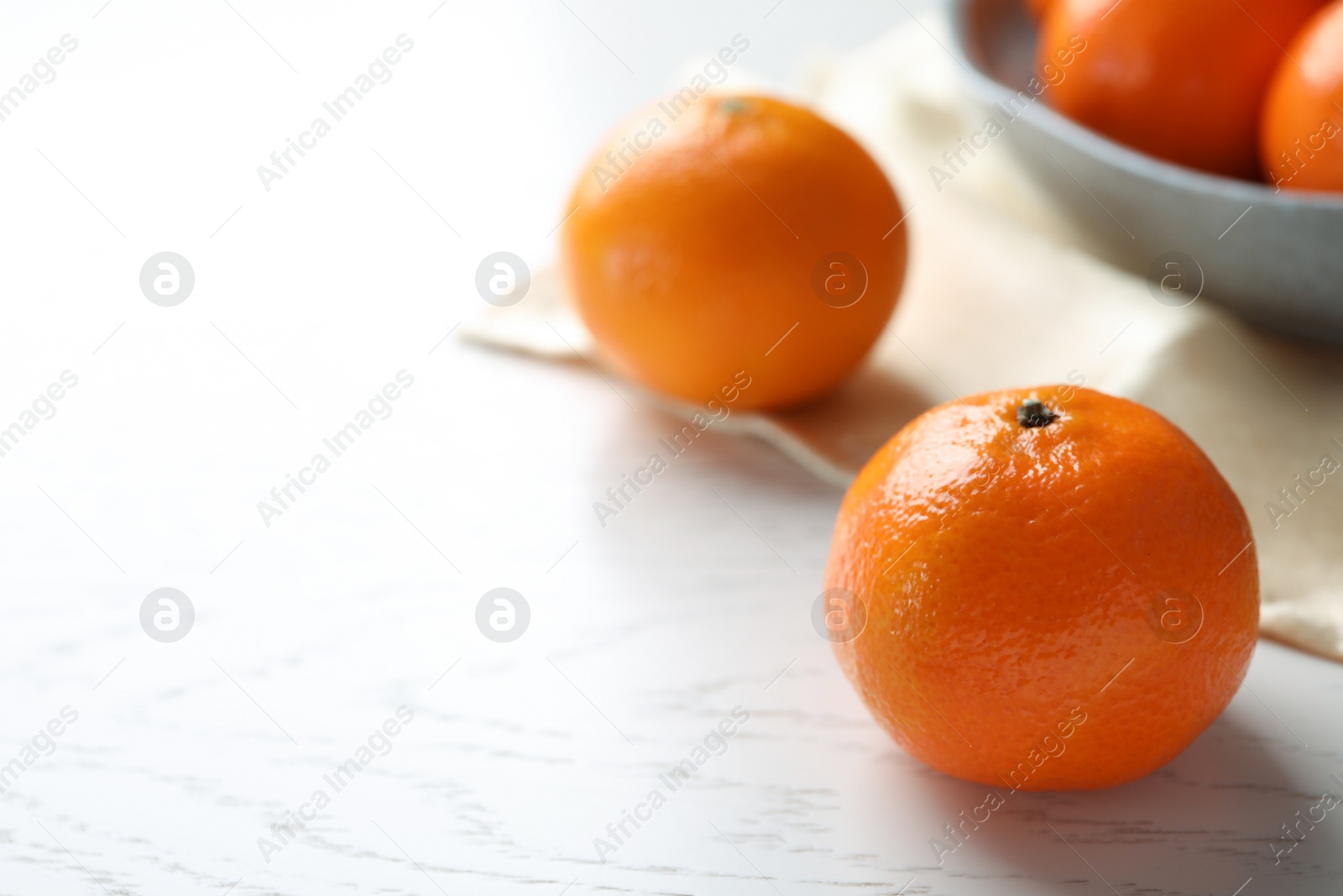 Photo of Fresh ripe tangerine on white wooden table, space for text]