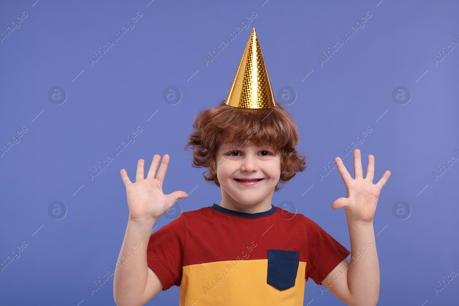 Photo of Cute little boy in party hat on purple background